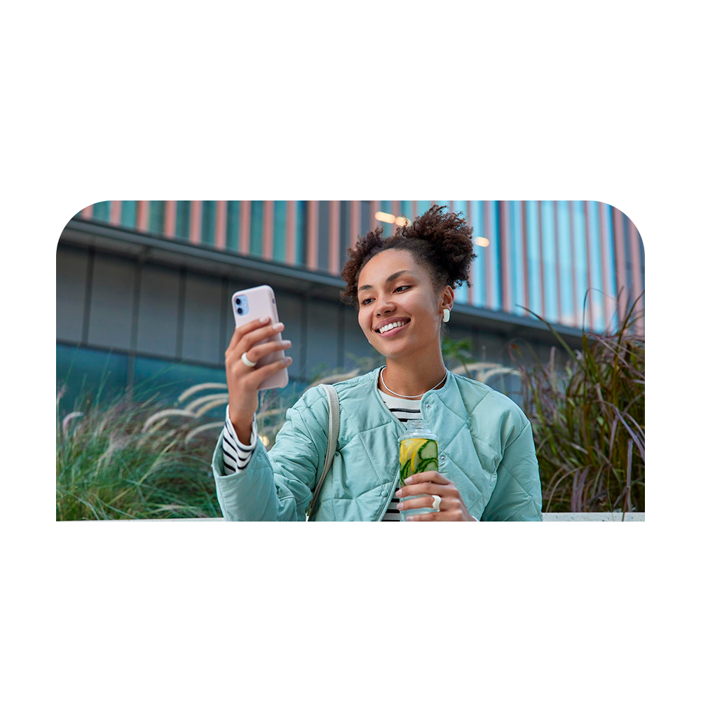 Pessoa sorrindo com celular ao ar livre